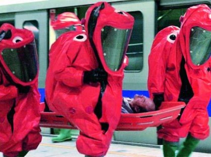 ludzie w czerwonych przeciwskażeniowych kombinezonach niosący na noszach człowieka