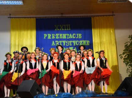 dziecięcy zespół występujący na scenie ubrany w stroje ludowe