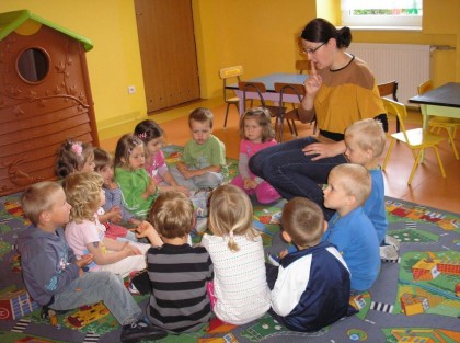 dzieci siedzące w kółko razem z opiekunką