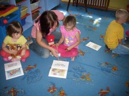 opiekunka rozmawia z dziewczynką na dywanie