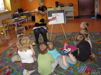 dzieci siedzące na dywanie słuchające swojej wychowawczyni