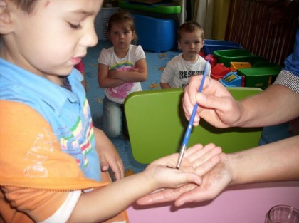 opiekunka maluje pędzelkiem rękę chłopca