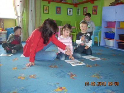 dzieci siedzące na niebieskim dywanie