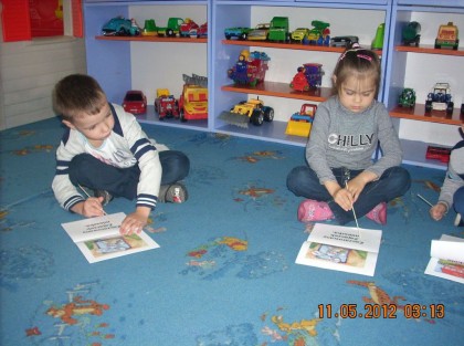 dwójka dzieci siedząca na dywanie w przedszolu